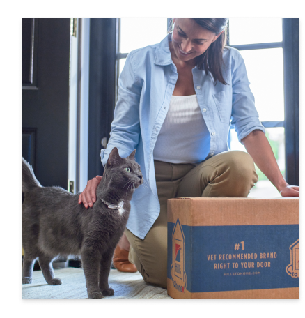 A woman with her black furry cat and Hill's Pet Cat Food package