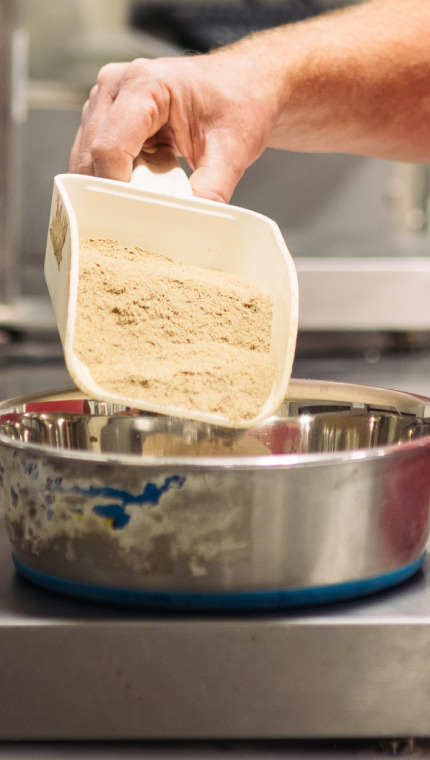 A Hill’s employee measuring ingredients on a scale